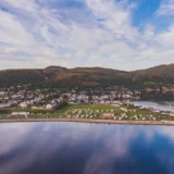 Aerial view of Ullapool and more so Broomfield Holiday Park, which is the Ullapool campsite. It sits next to the shires of Loch Broom in the Scottish Highlands. There is tents and campervans on the site. Captured by Marc Hilton